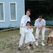 A happy family enjoys a game of tug of war in a grassy field by a house.